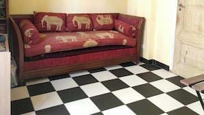 Un sofá rojo con diseños de elefantes, suelo a cuadros y una puerta de madera.