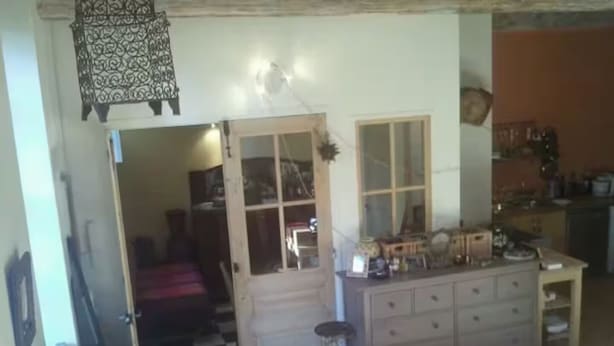 Una habitación con piso a cuadros, un armario de madera y una puerta que da a otra habitación.