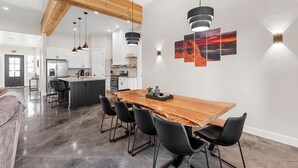 Una cocina moderna con armarios blancos, una isla de madera y sillas negras.