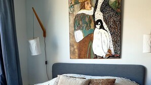 Een slaapkamer met een bed, een hanglamp en een schilderij aan de muur.