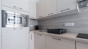 Een moderne keuken met een inbouwmagnetron, koffiezetapparaat en een spoelbak.