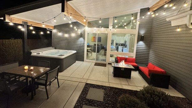 Eine Außenpatio-Terrasse mit Whirlpool, Sitzgelegenheiten und Lichterketten.