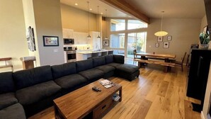 Ein modernes Wohnzimmer mit einer großen Eckcouch, einem Holztisch und einem Essbereich mit Tisch und Stühlen.