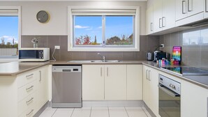 A modern kitchen with a dishwasher, microwave, and a colorful towel rack.