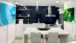 Une cuisine moderne avec des meubles blancs, un îlot central et un revêtement mural noir.