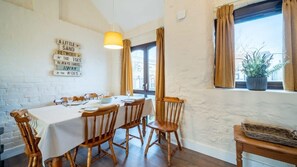 A dining area with a table for four, wooden chairs, and a potted plant on the windowsill.