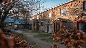 Traditional stone building with a central entrance and symmetrical facade, set amidst a serene and secluded environment.