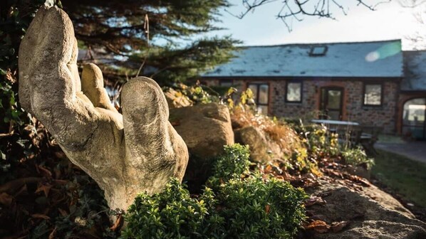 Situated in a serene landscaped garden, this natural rock formation resembles a hand, surrounded by well-maintained shrubs.