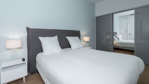 Une chambre moderne avec un grand lit, deux tables de chevet avec des lampes et une porte de placard coulissante.