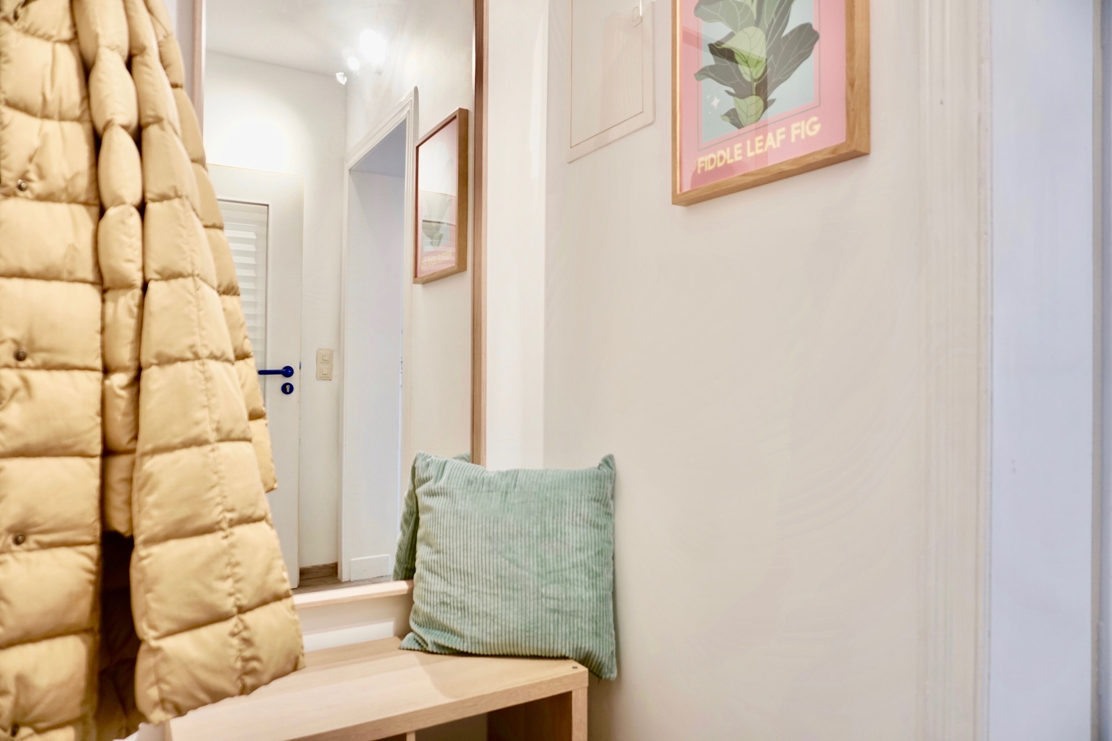 A hallway with a potted plant, a framed picture, and a bench.