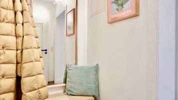 A hallway with a potted plant, a framed picture, and a bench.