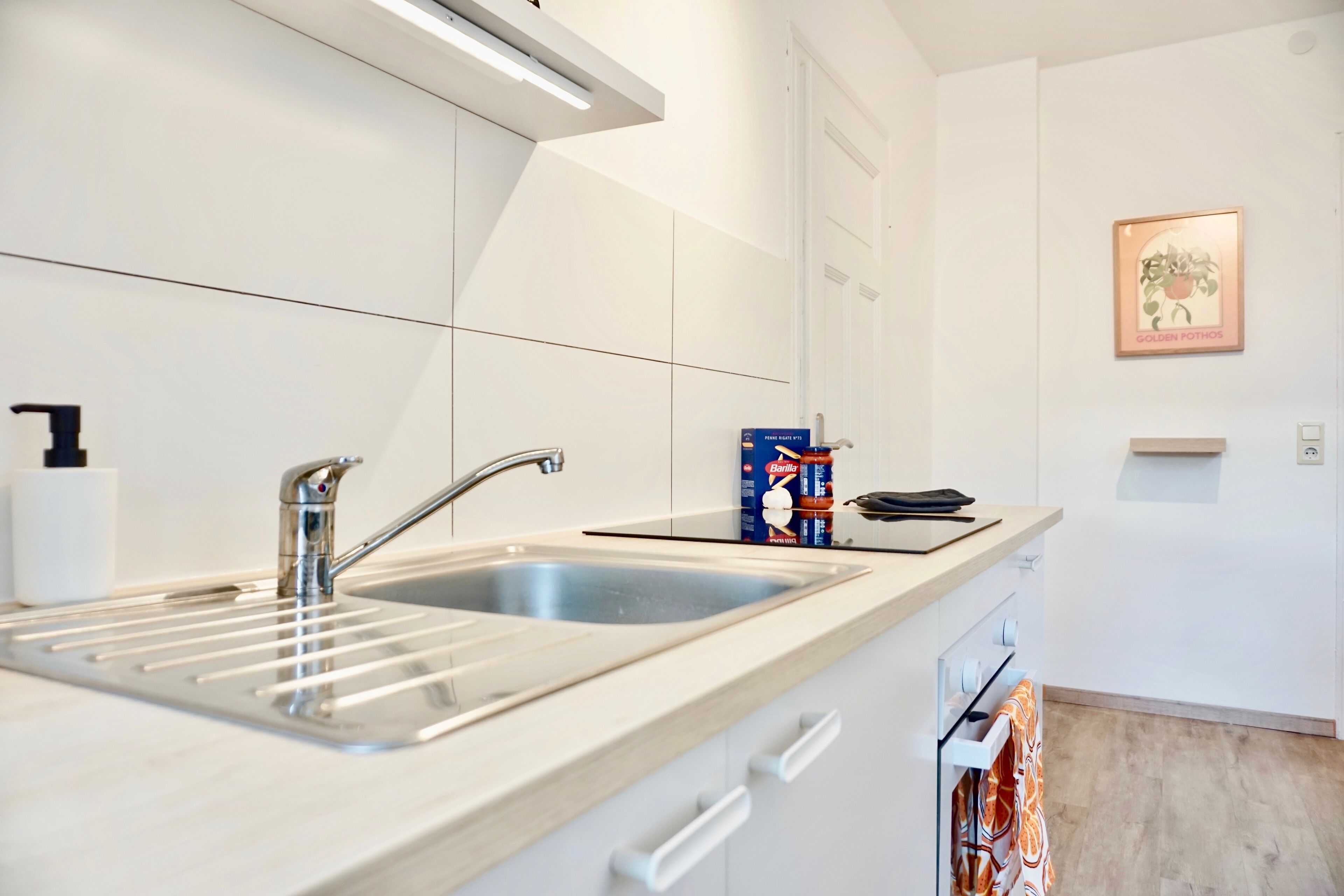A modern kitchen with a double sink, white cabinets, and a countertop with a box of baking soda.