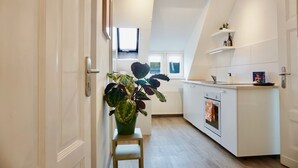 Een moderne keuken met witte kasten, een klein eiland en een potplant.
