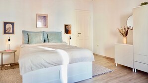Ein Schlafzimmer mit Bett, Nachttischen, einem Schminktisch und einer Tür.