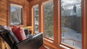 A wooden cabin interior with a large window, a wooden bench, and a view of a snowy landscape. - Kings Crossing Townhome 12 New Downtown 3 bedroom Private Hot Tub (Winter Park)