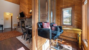 A cozy room with a stone fireplace, wooden walls, a black leather chair, and a wooden desk. - Kings Crossing Townhome 12 New Downtown 3 bedroom Private Hot Tub (Winter Park)