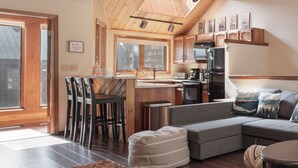A modern kitchen with a skylight, wooden ceiling, and a dining area with chairs and a table. - Kings Crossing Townhome 12 New Downtown 3 bedroom Private Hot Tub (Winter Park)