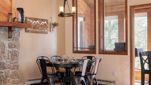 A dining area with a stone wall, a chandelier, and a window with blinds. - Kings Crossing Townhome 12 New Downtown 3 bedroom Private Hot Tub (Winter Park)