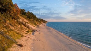 A beach with a staircase leading down to the shore, surrounded by trees and a clear sky.