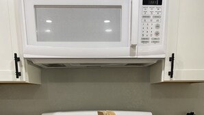 A kitchen with a white stove, a microwave above it, and various cooking utensils on the counter. - Riverfront Retreat on deep canal with Hot Tub,  Clear Kayaks & Fire pit (Spring Hill)