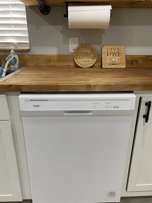 Een keuken met een vaatwasser, een houten aanrechtblad en twee decoratieve borden.