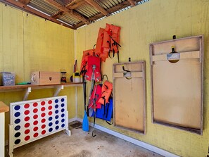 Une pièce avec un mur jaune, une étagère en bois, une boîte de rangement et un porte-gilets de sauvetage.