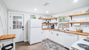 A modern kitchen with white cabinets, wooden countertops, and a built-in stove. There is a refrigerator, a sink, and various kitchen appliances. - Riverfront Retreat on deep canal with Hot Tub,  Clear Kayaks & Fire pit (Spring Hill)