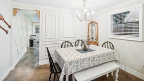A dining room with a table set for four, a chandelier, and a window with blinds. - Riverfront Retreat on deep canal with Hot Tub,  Clear Kayaks & Fire pit (Spring Hill)