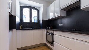 A modern kitchen with white cabinets, a black countertop, and a built-in oven. - Florella Residences 2 pièces Antibes (Cannes)