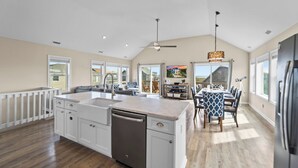 A spacious kitchen with a central island, a dining area with a large table, and a view of the outdoors.