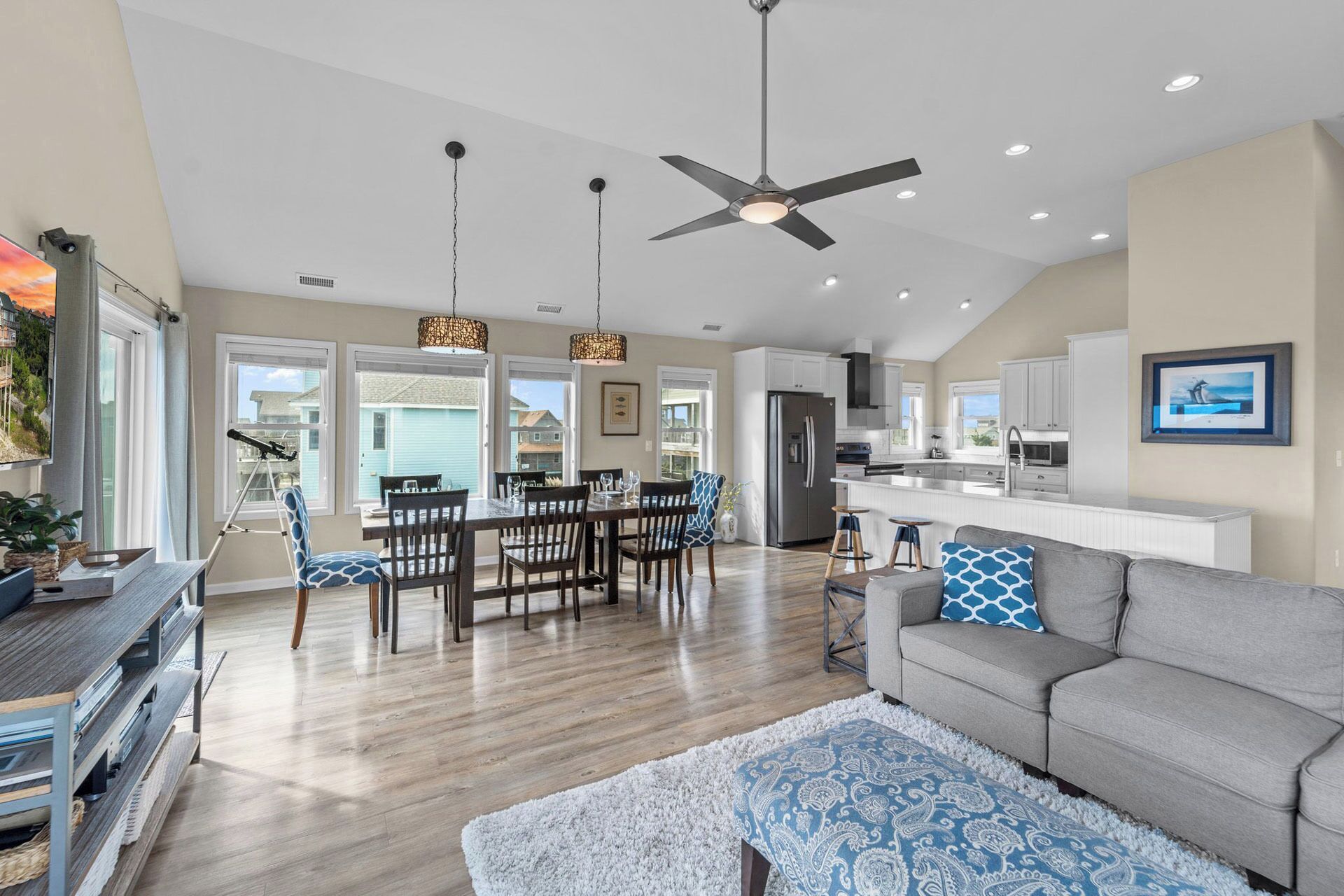 A spacious living area with a grey sofa, a patterned rug, and a dining area with wooden chairs and a table.