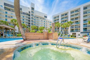 A hotel pool area with a hot tub, lounge chairs, and a wooden deck. - Gulf Shores Surf and Racquet Club 702B (Gulf Shores)