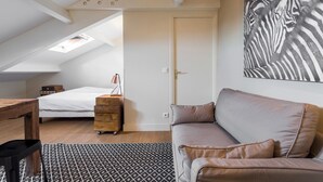 Een slaapkamer met een schuine kap, een bed, een dressoir, een bank en een muurschildering van een zebra.