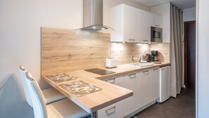 Une cuisine moderne dotée d’un plan de travail en bois, de meubles blancs, d’un four encastré et d’une machine à café.