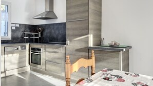 Una cocina moderna con horno empotrado, extractor de acero inoxidable y una silla de madera.