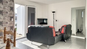 Una sala de estar moderna con un sofá negro, un televisor y una lámpara de pie.