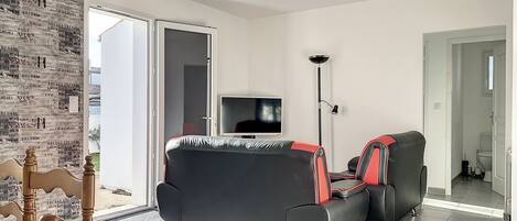 A modern living room with a black sofa, a television, and a floor lamp.
