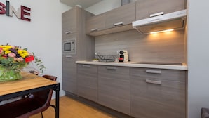 A modern kitchen with wooden cabinets, a built-in oven, and a coffee machine.