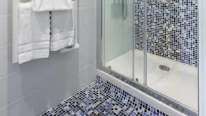 A modern bathroom with a glass-enclosed shower, tiled walls, and a mosaic floor.