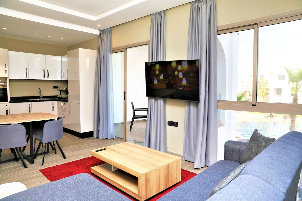 A modern living room with a sofa, a coffee table, and a TV mounted on the wall.