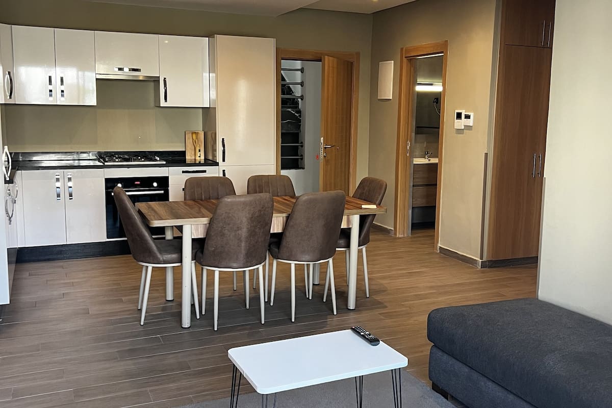 A modern living room with a sofa, a coffee table, and a dining area with chairs and a table.