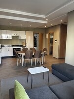 Una sala moderna con un sofá, una mesita de centro y un comedor con sillas y una mesa.