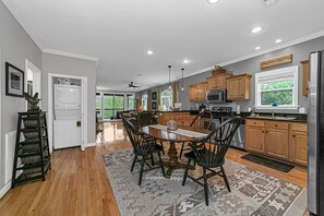 Una cocina moderna con armarios de madera, una isla central y un comedor con sillas.