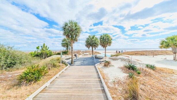 A wooden boardwalk leading to a beach with palm trees and sandy dunes. - Relaxing 2 BR cottage, walking distance to beach (Hilton Head Island)