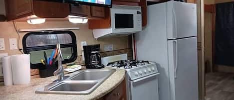 A compact kitchen with a microwave, stove, and refrigerator.