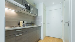 Una cucina moderna con forno a microonde, macchina del caffè e lavello. Si nota una porta bianca e un pavimento in legno.