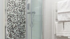 Un bagno moderno con doccia vetrata, pavimento piastrellato e pareti bianche.