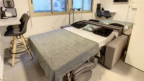 Een kleine kamer met een bed, bureau, stoel en televisie.