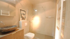 A bathroom with a stone sink, a toilet, a shower with a glass door, and a towel rack. - Cosy studio in Cannes (Cannes)