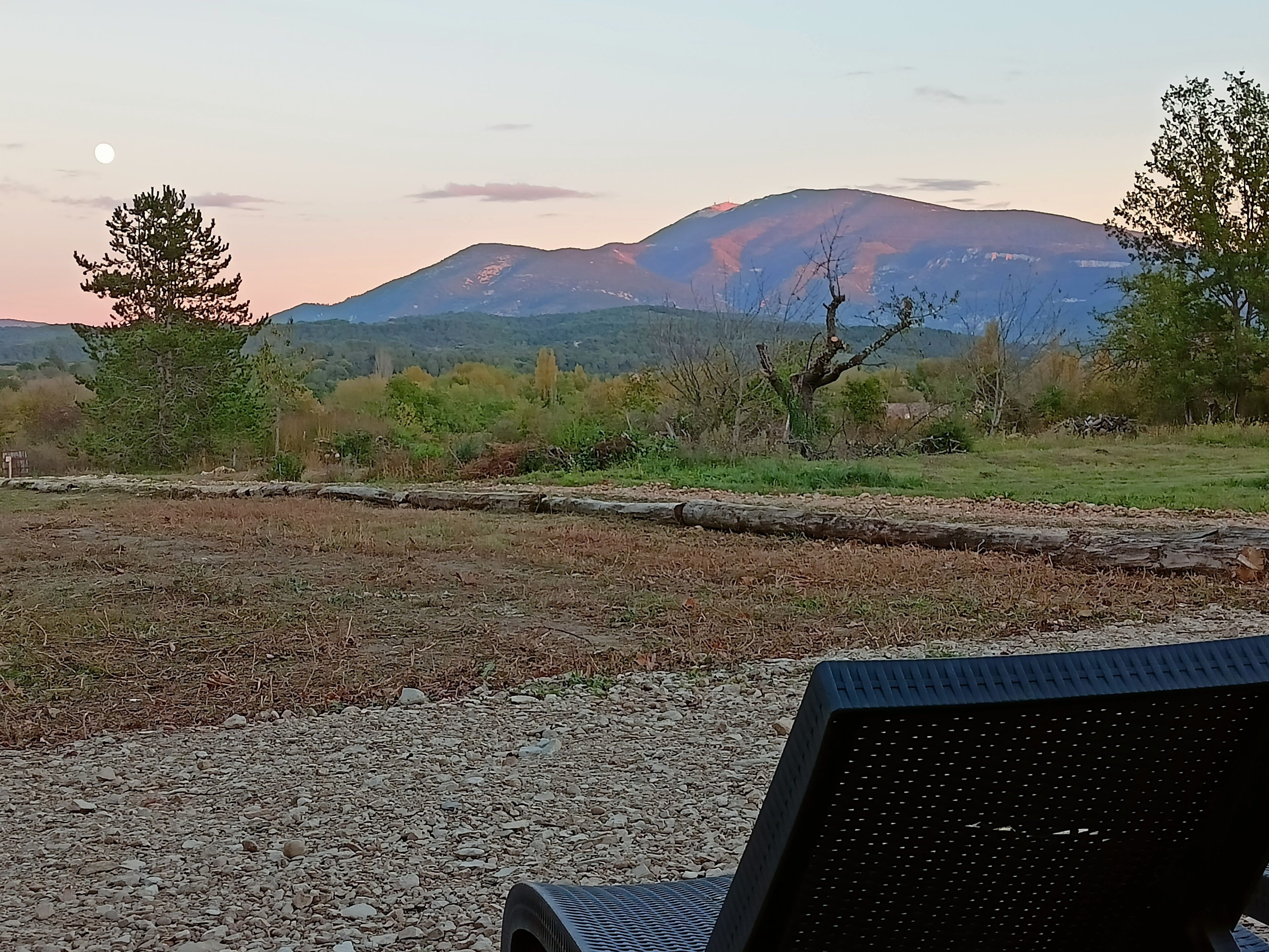A gravel area with a chair and a view of a mountain range.